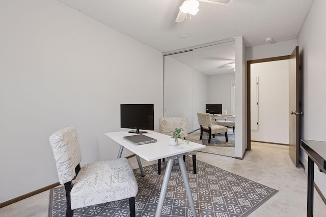 office area featuring baseboards, a ceiling fan, a textured ceiling, and light carpet
