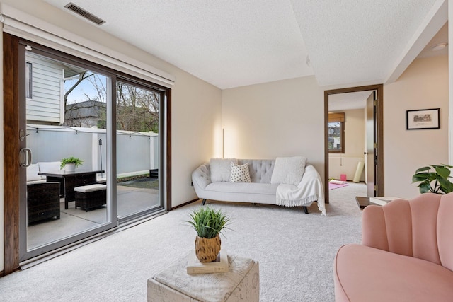 living room featuring carpet floors, a textured ceiling, and visible vents