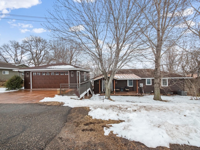 view of front of house featuring central AC, covered porch, a garage, and aphalt driveway