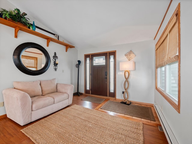 foyer featuring baseboards, a baseboard heating unit, wood finished floors, and lofted ceiling
