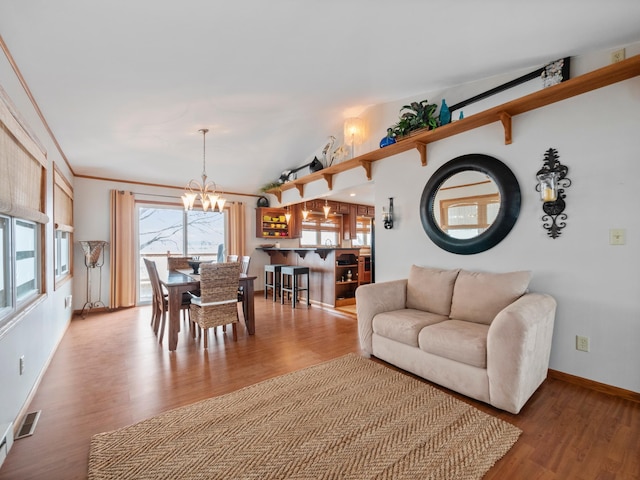 living area featuring baseboards, wood finished floors, a notable chandelier, and visible vents
