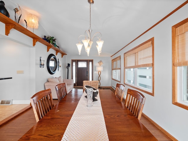 dining space with a notable chandelier, visible vents, baseboards, and wood finished floors