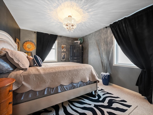 carpeted bedroom featuring baseboards, multiple windows, and an inviting chandelier