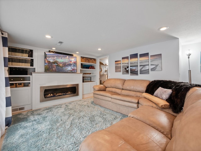 living area featuring visible vents, recessed lighting, and a glass covered fireplace