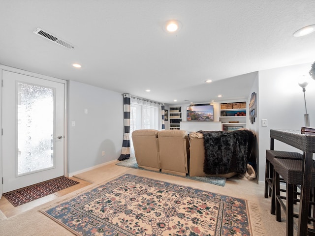 living area featuring light carpet, a healthy amount of sunlight, visible vents, and recessed lighting