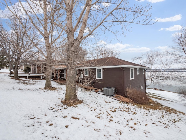 snow covered rear of property with a deck and central AC unit