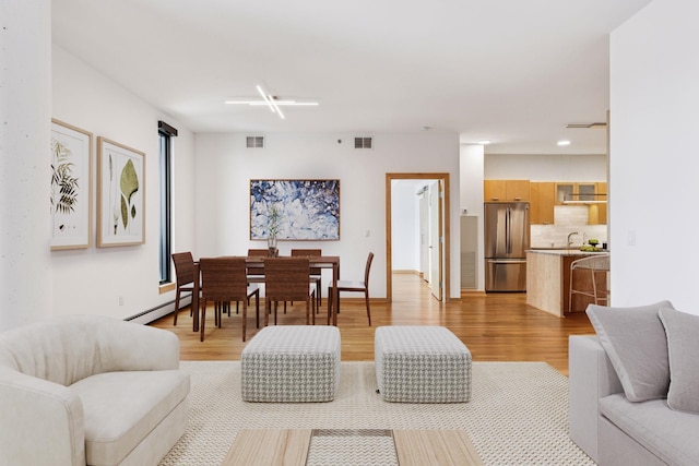 living room with visible vents, a baseboard radiator, and light wood-style floors