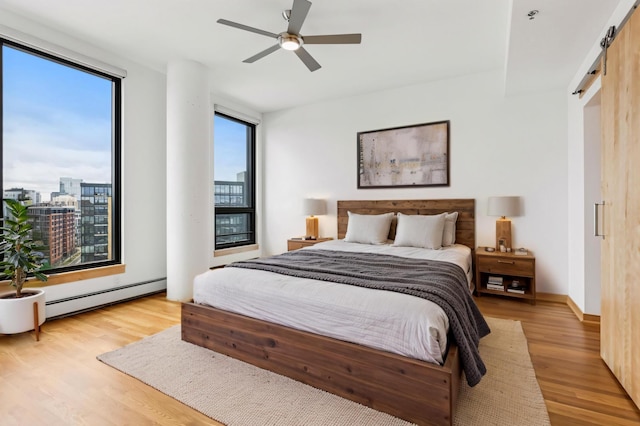 bedroom featuring a baseboard radiator, multiple windows, and light wood-style flooring