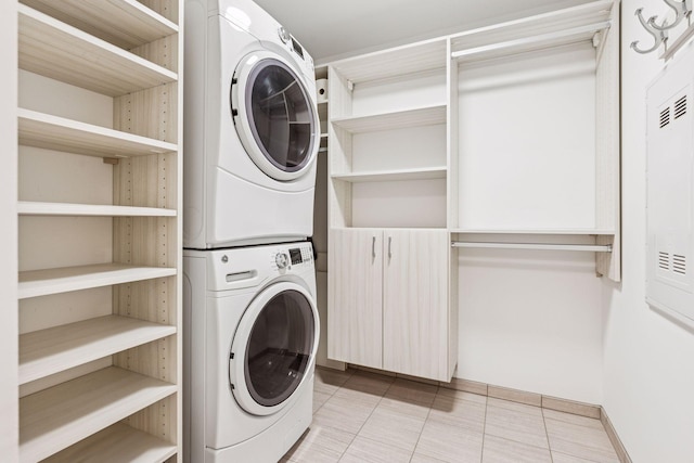 clothes washing area featuring light tile patterned floors, laundry area, and stacked washer and clothes dryer