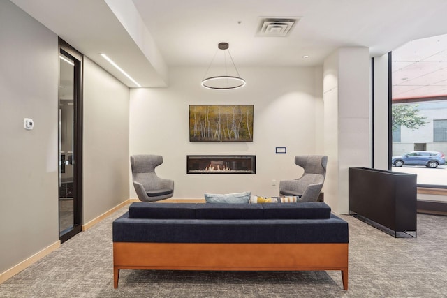 sitting room featuring a glass covered fireplace, baseboards, carpet, and visible vents