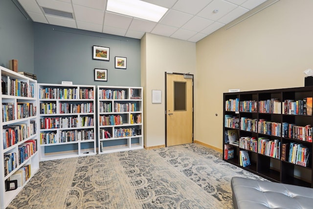 sitting room featuring visible vents, a paneled ceiling, and bookshelves