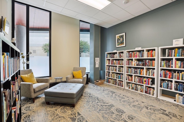 living area with wall of books and a drop ceiling