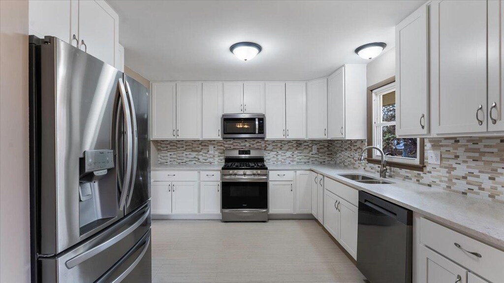 12025 Florida Ave N, Champlin, MN 55316 - kitchen featuring tasteful backsplash, white cabinets, a sink, and stainless steel appliances