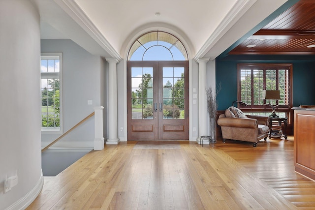 entrance foyer featuring ornate columns, wood-type flooring, a healthy amount of sunlight, and french doors