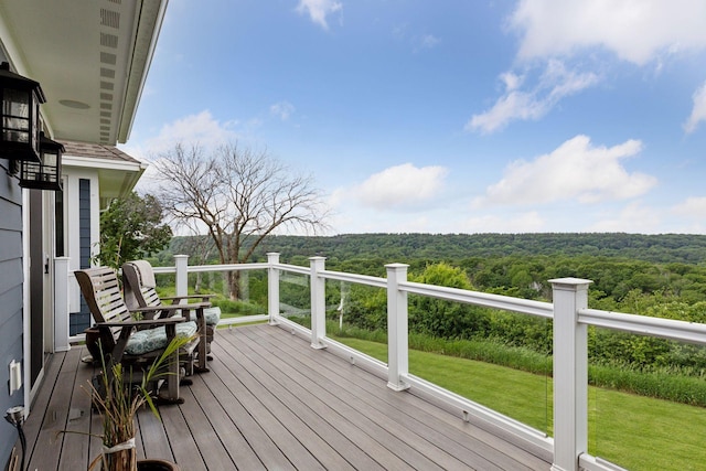 wooden deck with a lawn and a forest view
