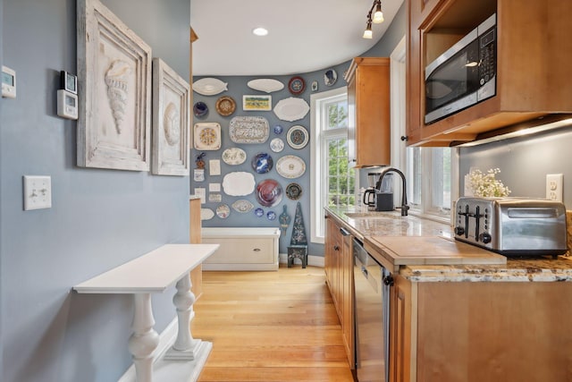 kitchen featuring brown cabinets, light wood-type flooring, a sink, a toaster, and stainless steel appliances