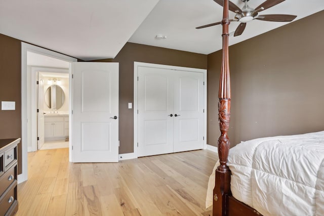 bedroom with a sink, light wood-style floors, a ceiling fan, baseboards, and a closet