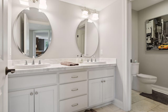 full bath featuring double vanity, a sink, baseboards, and toilet