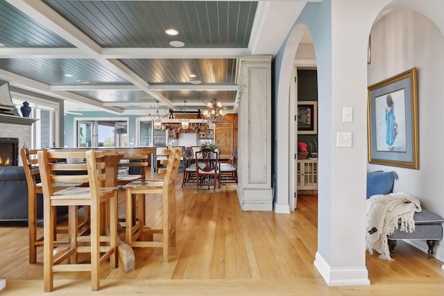 dining room featuring arched walkways, beam ceiling, baseboards, recessed lighting, and hardwood / wood-style floors
