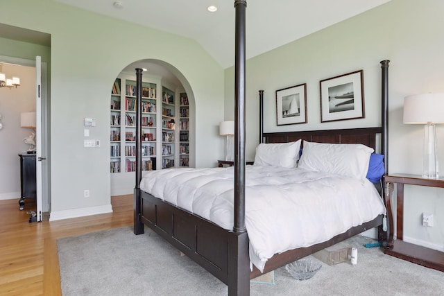 bedroom with baseboards, wood finished floors, and vaulted ceiling