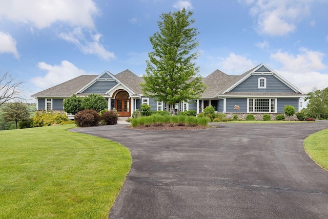 view of front of house featuring a shingled roof, a front lawn, aphalt driveway, and french doors