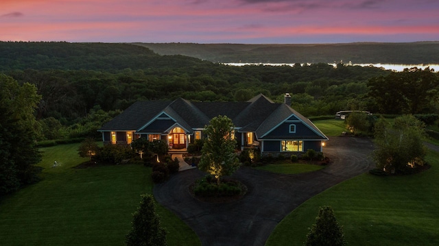 craftsman house featuring a water view, a view of trees, a chimney, and curved driveway