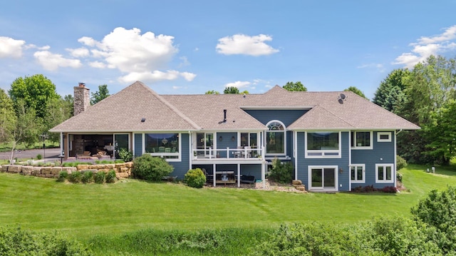 back of property featuring roof with shingles, a garage, a chimney, a patio area, and a lawn