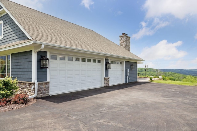 view of property exterior featuring a shingled roof, a chimney, a garage, and stone siding