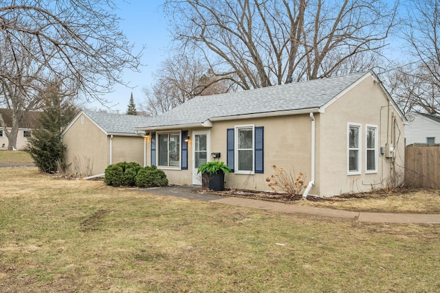 view of front of property featuring stucco siding, fence, roof with shingles, and a front yard