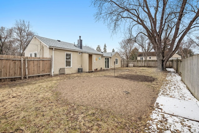 rear view of property featuring a fenced backyard, stucco siding, and a chimney
