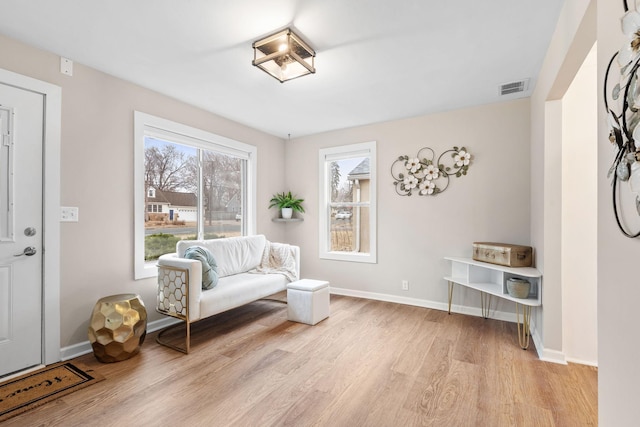 living area with baseboards, visible vents, and light wood-type flooring