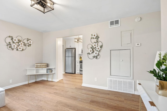 interior space featuring light wood-type flooring, baseboards, and visible vents