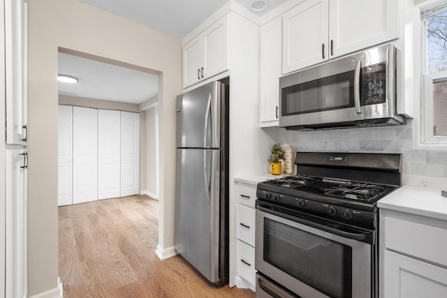 kitchen with light countertops, light wood-style flooring, stainless steel appliances, backsplash, and white cabinets