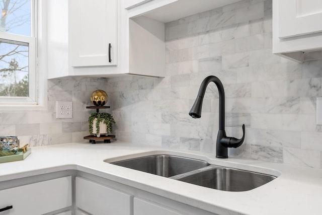 kitchen featuring white cabinetry, light countertops, a sink, and decorative backsplash