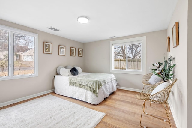 bedroom with wood finished floors, baseboards, and visible vents
