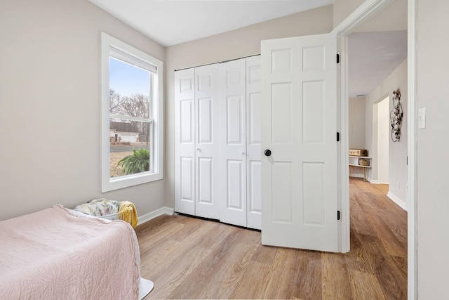 bedroom with a closet, baseboards, and light wood-style floors