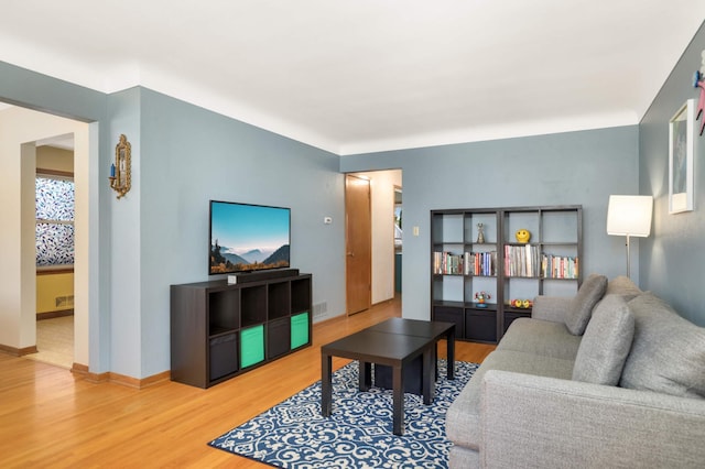 living area featuring baseboards, visible vents, and wood finished floors