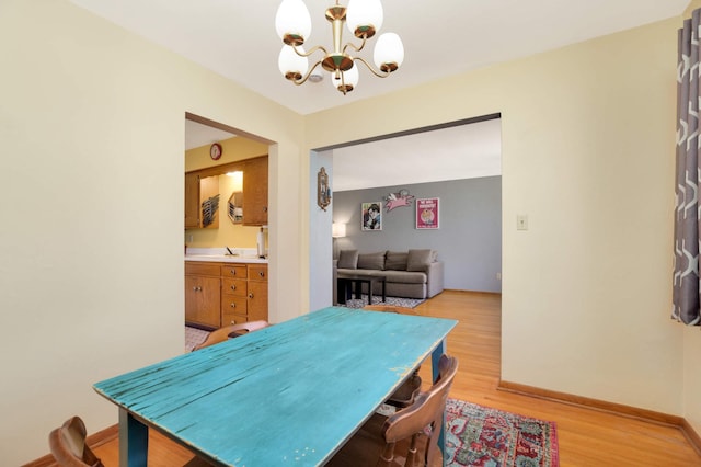 dining space with baseboards, an inviting chandelier, and light wood-style floors