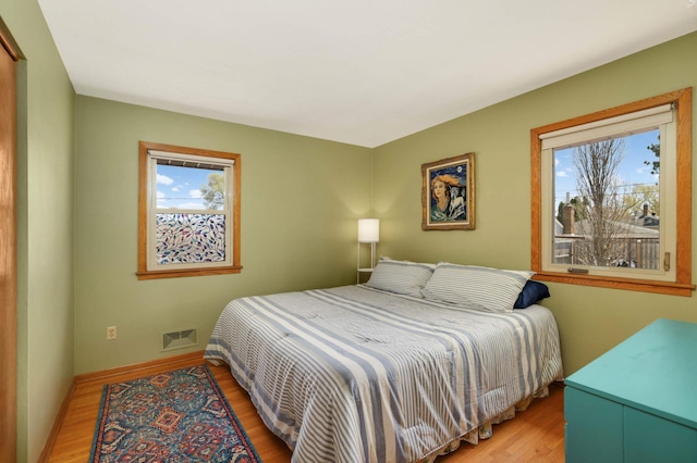 bedroom with baseboards, wood finished floors, and visible vents