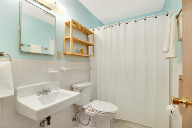 full bath featuring tile patterned flooring, wainscoting, curtained shower, toilet, and tile walls