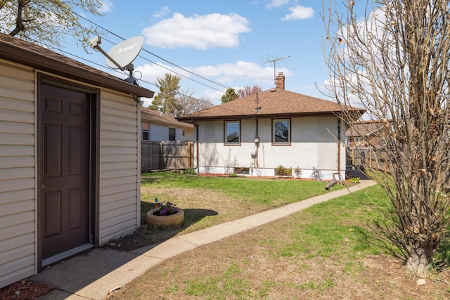 rear view of house featuring fence, a shingled roof, a chimney, a lawn, and an outdoor structure