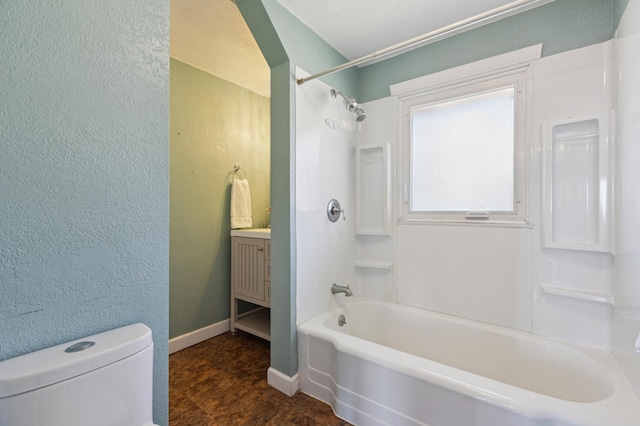 full bathroom featuring bathtub / shower combination, vanity, toilet, a textured wall, and baseboards