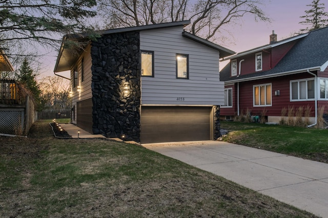 view of front of property featuring driveway, a chimney, a garage, a front lawn, and stone siding