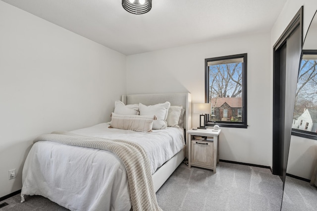 bedroom with baseboards, visible vents, and light carpet