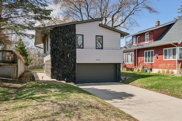 view of front of home featuring concrete driveway, a garage, stone siding, and a front lawn
