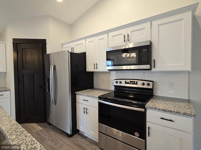 602 Warren St, Janesville, MN 56048 - kitchen with tasteful backsplash, vaulted ceiling, stainless steel appliances, white cabinets, and wood finished floors