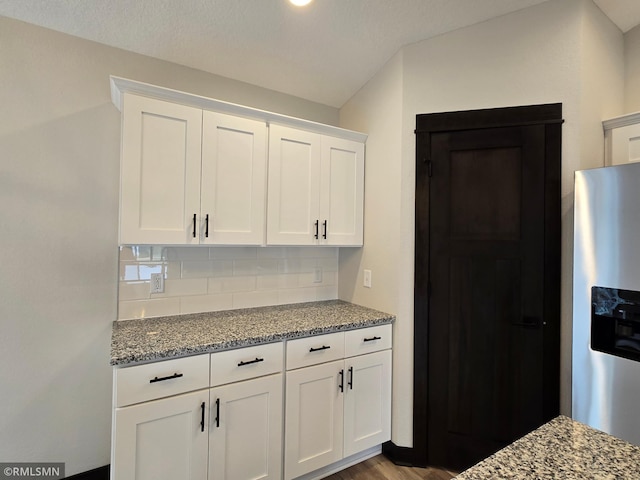 602 Warren St, Janesville, MN 56048 - kitchen featuring stainless steel fridge with ice dispenser, white cabinetry, light stone countertops, and tasteful backsplash