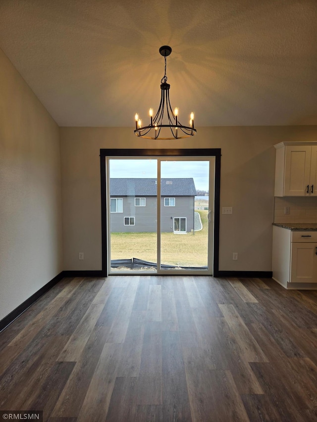 602 Warren St, Janesville, MN 56048 - unfurnished dining area featuring baseboards, an inviting chandelier, and dark wood finished floors