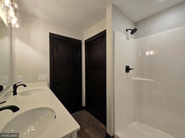 602 Warren St, Janesville, MN 56048 - bathroom with double vanity, a textured ceiling, a sink, and walk in shower