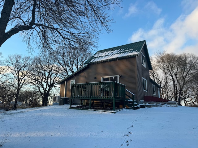 snow covered property featuring metal roof, central air condition unit, and a deck